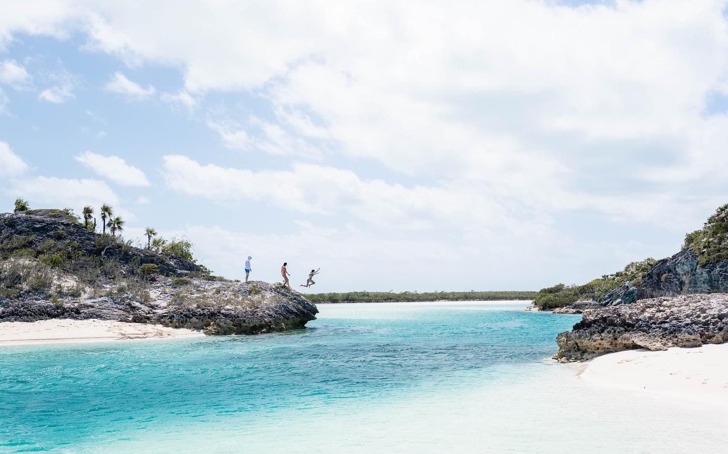 Guests cliff jumping into turquoise inlet