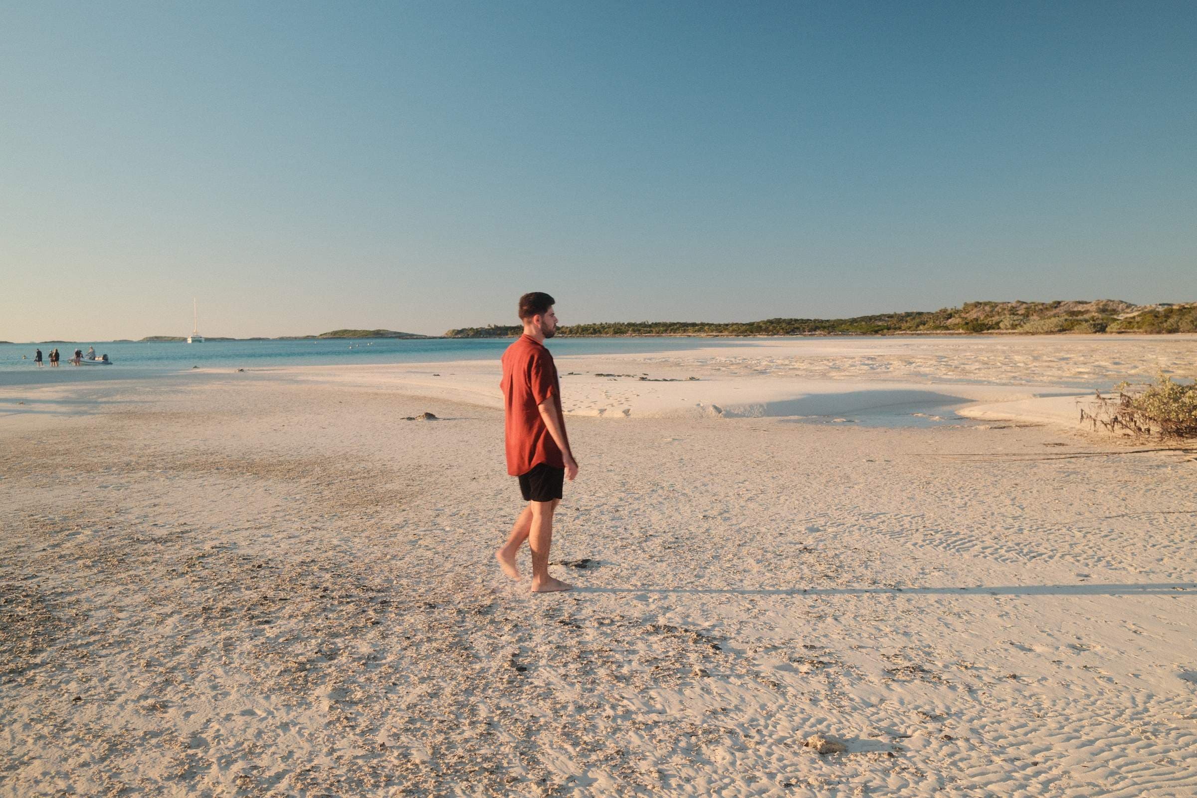 Man walking white sand, turquoise lagoon at Pipe Creek
