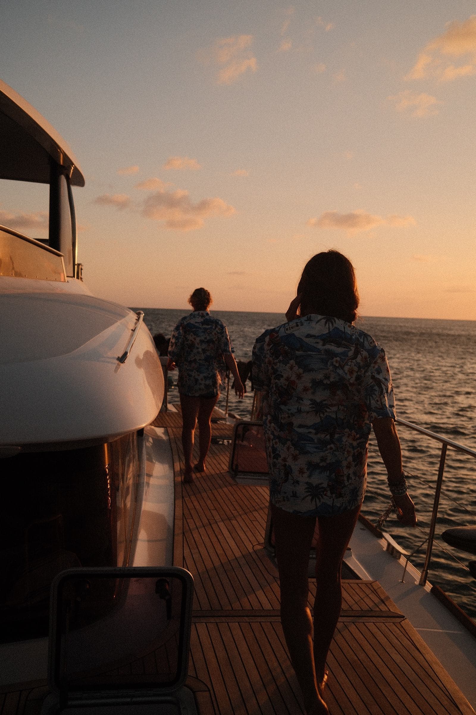 Guests walking yacht deck toward sunset
